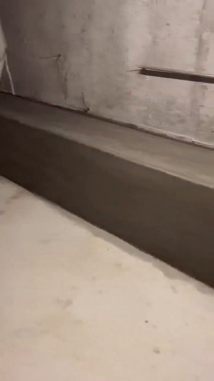 Finished smooth concrete retaining wall along a basement wall.