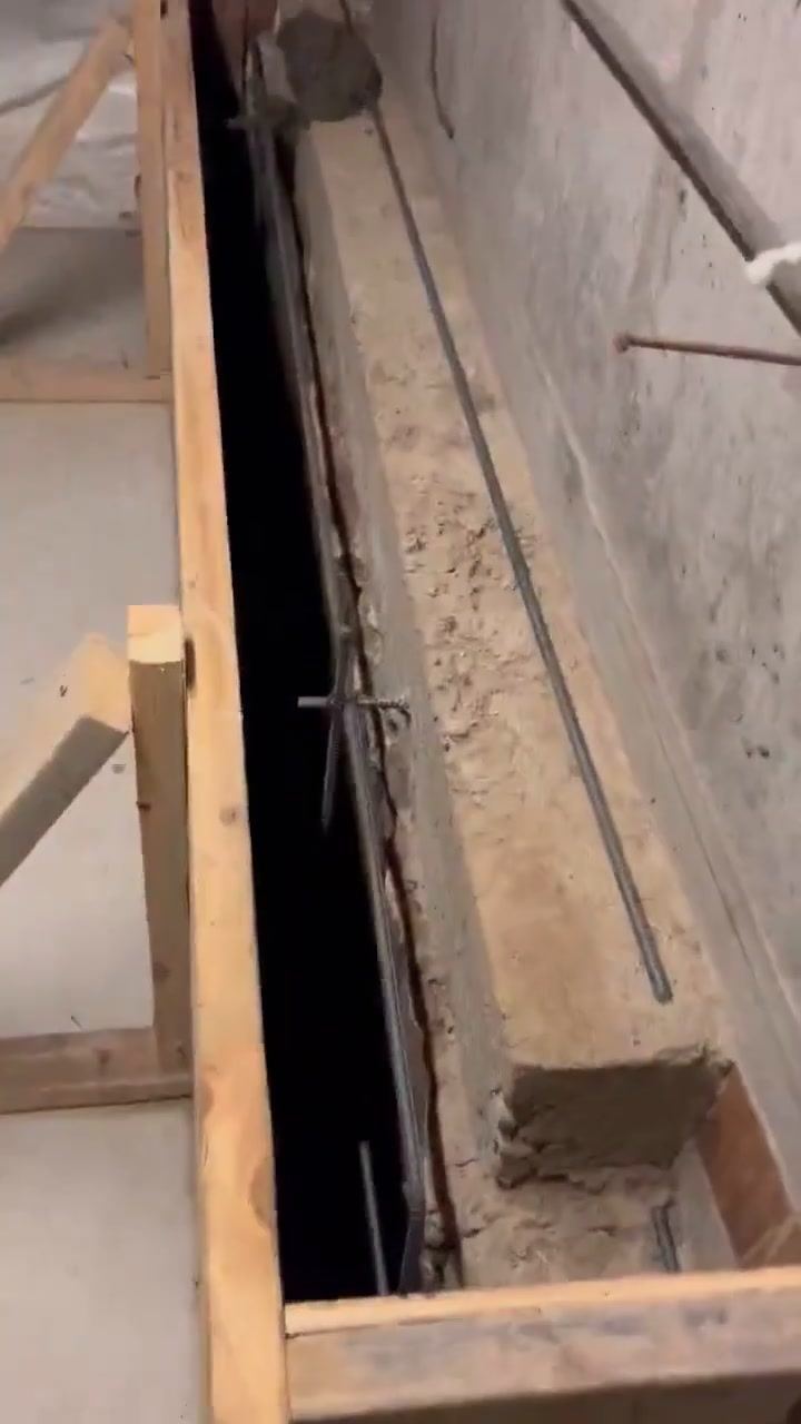 Wood forms and rebar set against a basement wall before a concrete pour.
