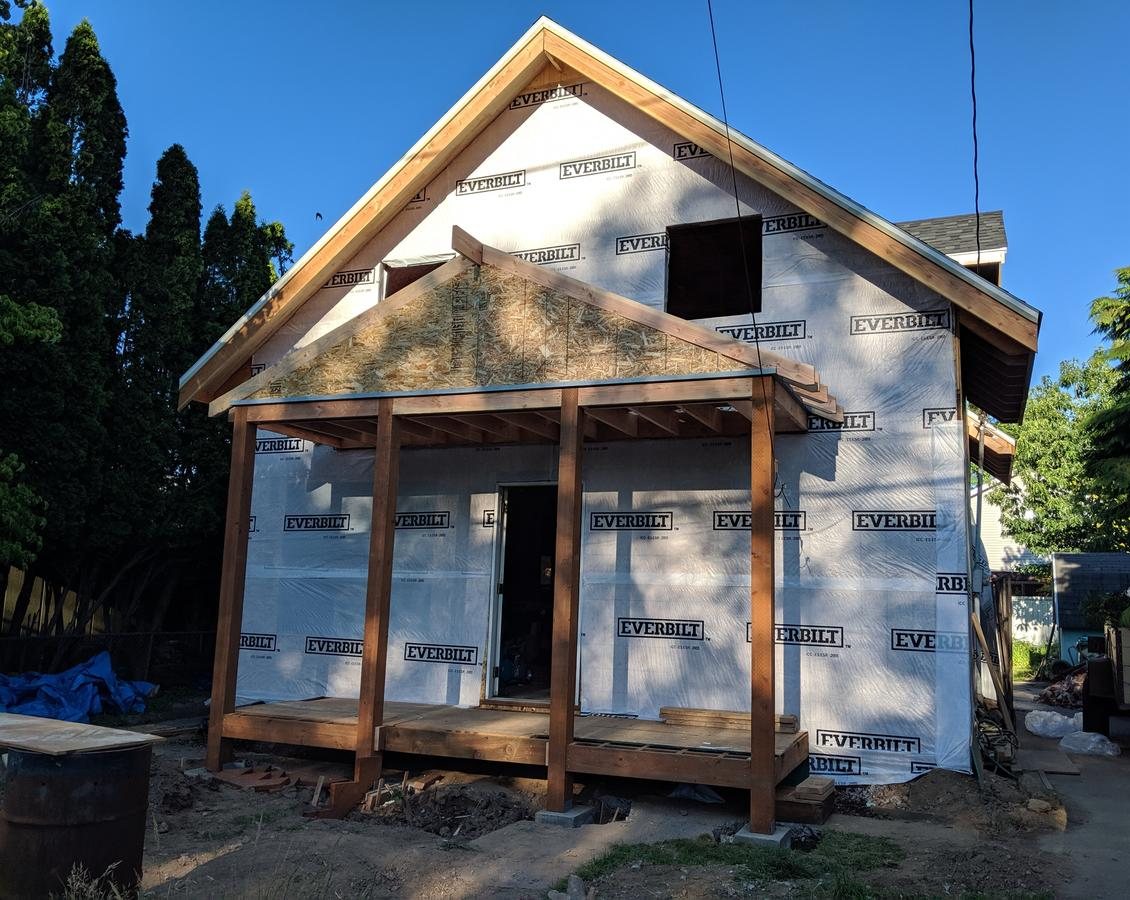 Remodel wrapped in house wrap before siding, with a new framed front porch