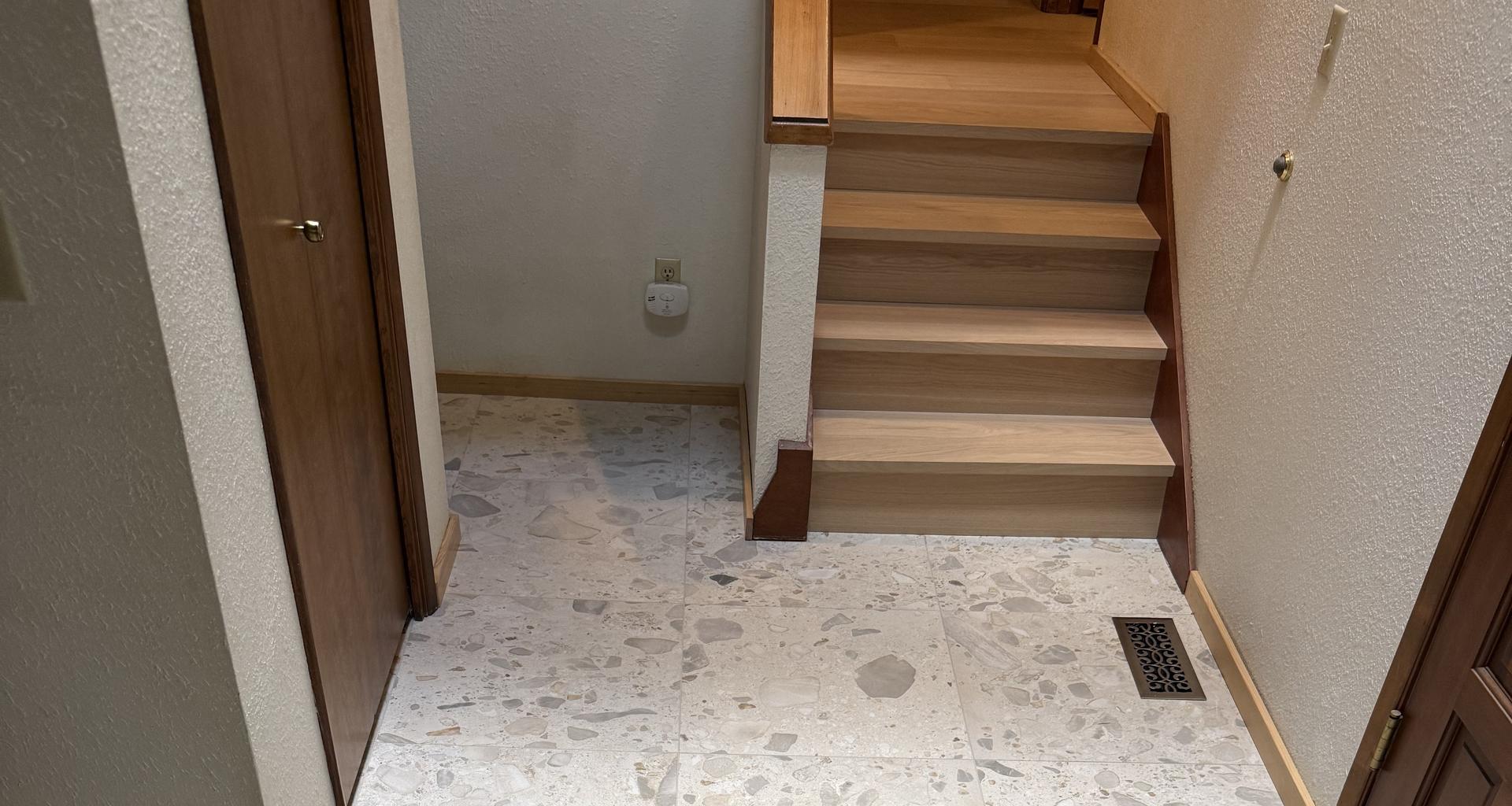 New terrazzo-look tile hallway and light wood-tone stair treads in a Portland-area home