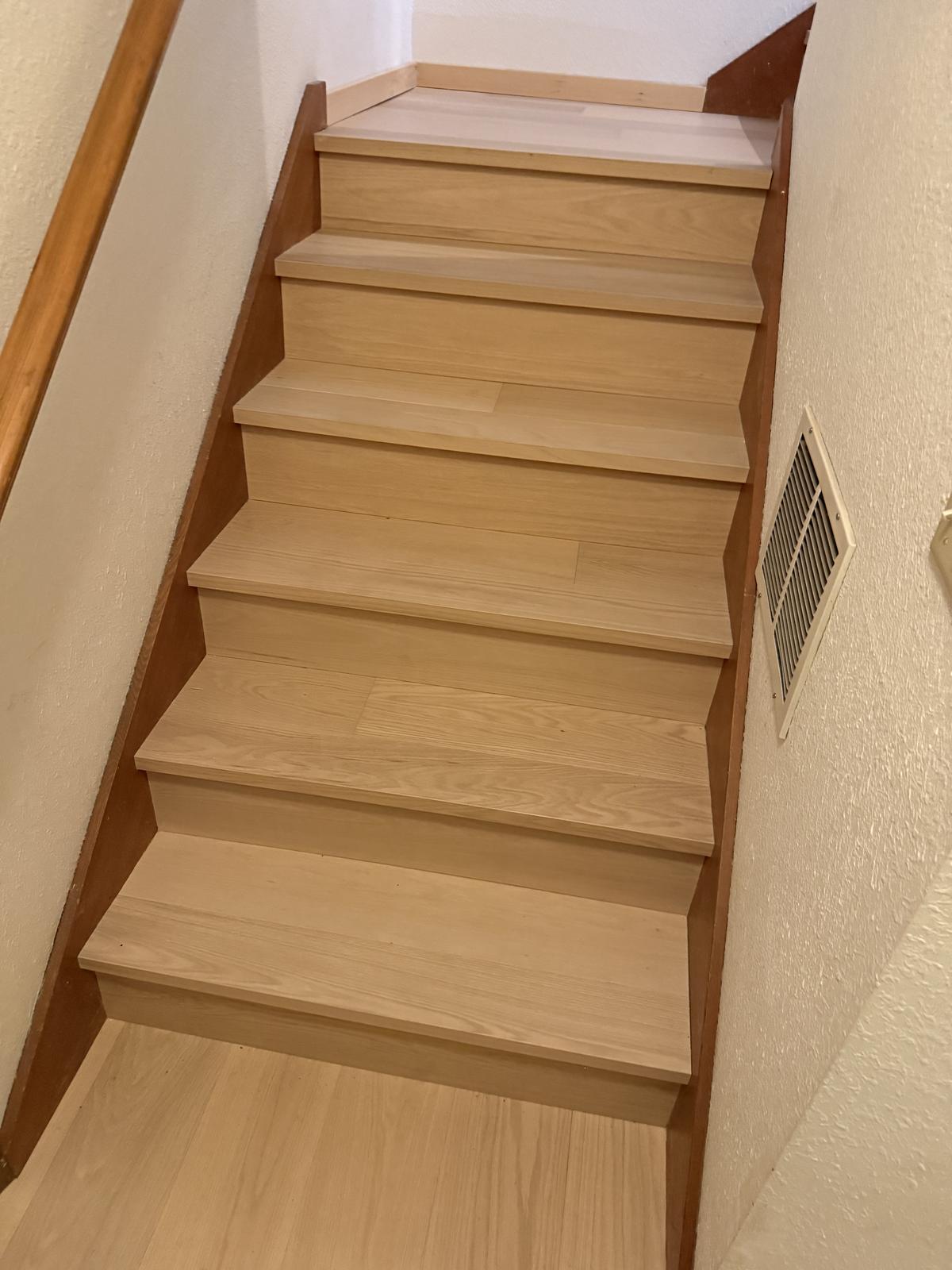 Staircase with light wood-tone treads and risers in a Portland-area flooring project
