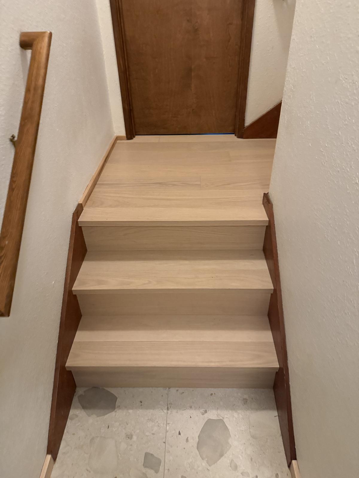 Stairs with new wood-tone treads above a terrazzo-look tile landing, Portland-area flooring