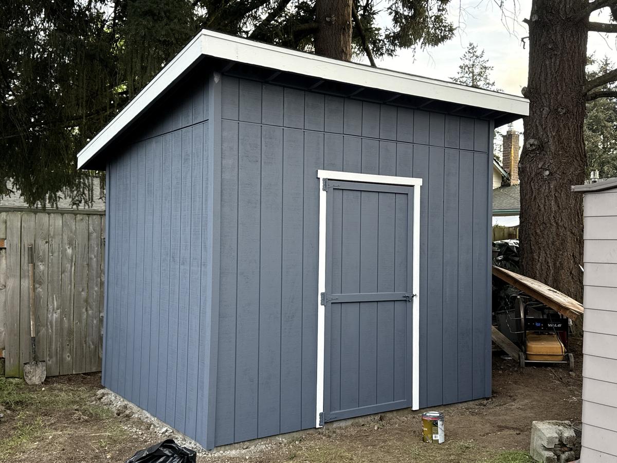 Finished gray backyard shed with white door trim built in Portland