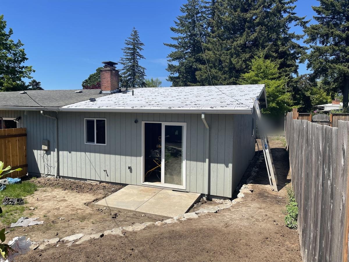 Finished Portland house addition with painted gray siding and sliding glass door