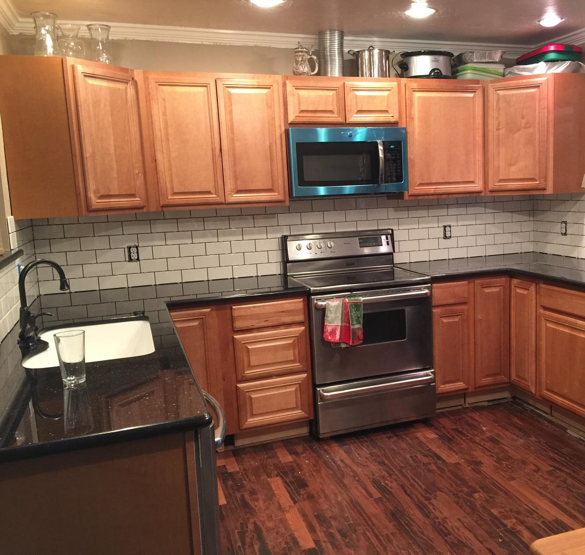 Finished U-shaped kitchen remodel in Portland with subway tile, wood cabinets and recessed lights