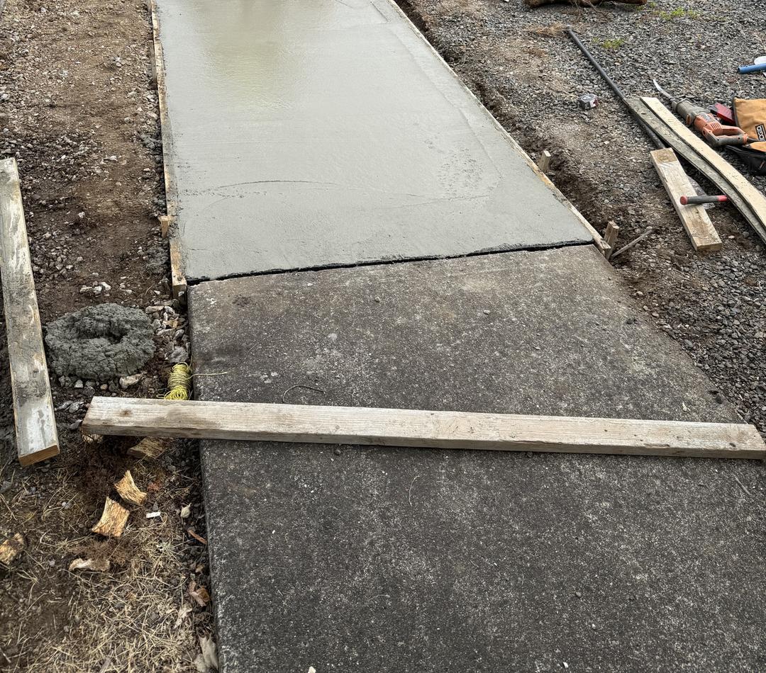 Freshly finished concrete section from a Portland sidewalk repair, next to the existing walk