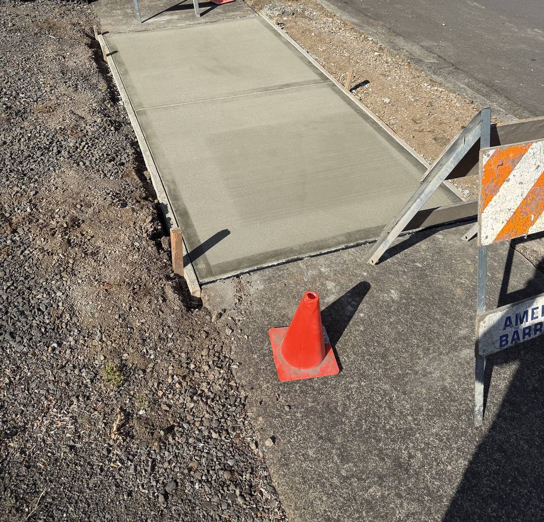 New concrete sidewalk panel from a Portland sidewalk repair, curing behind barricades
