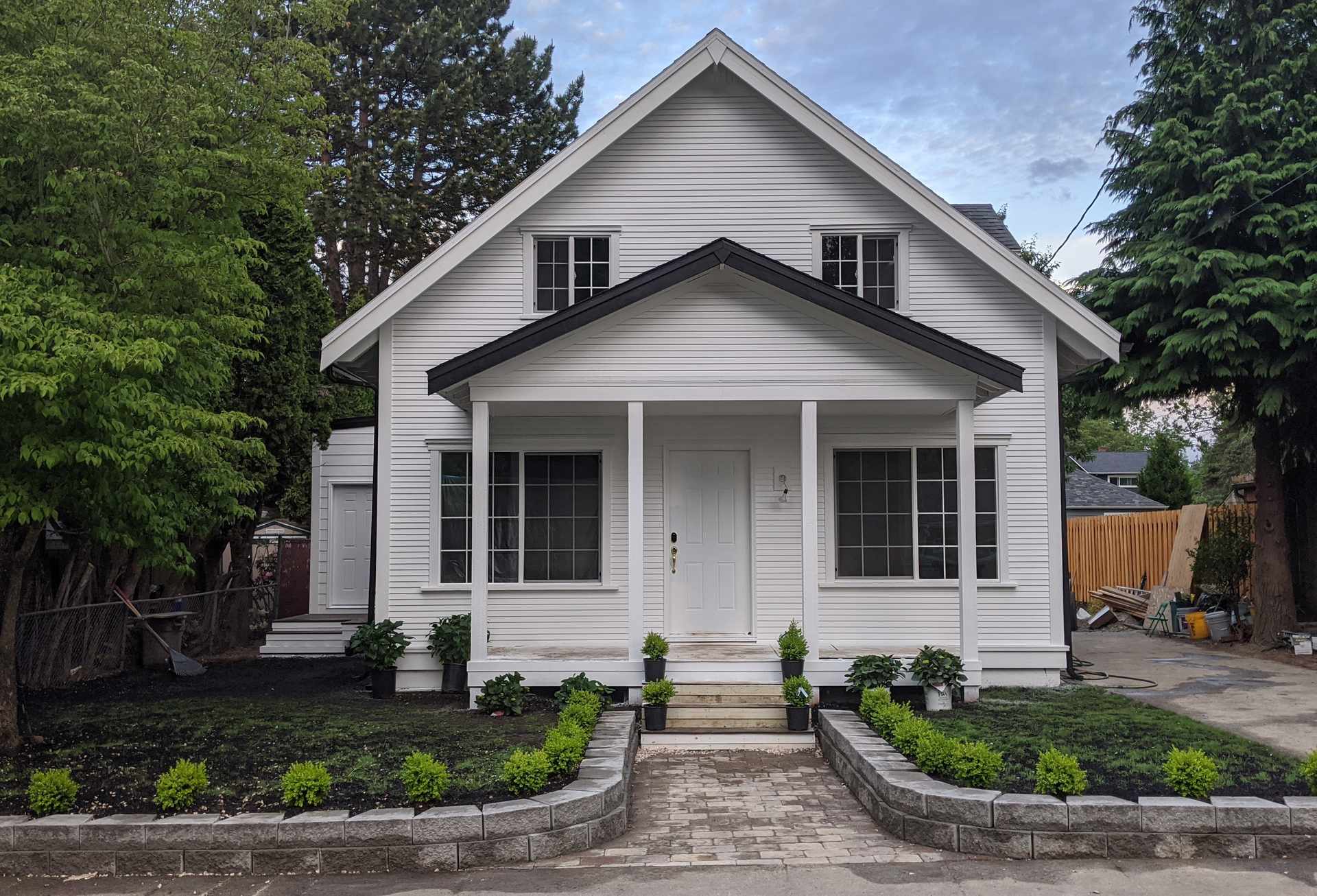 Remodeled home with white lap siding, covered front porch and paver walkway