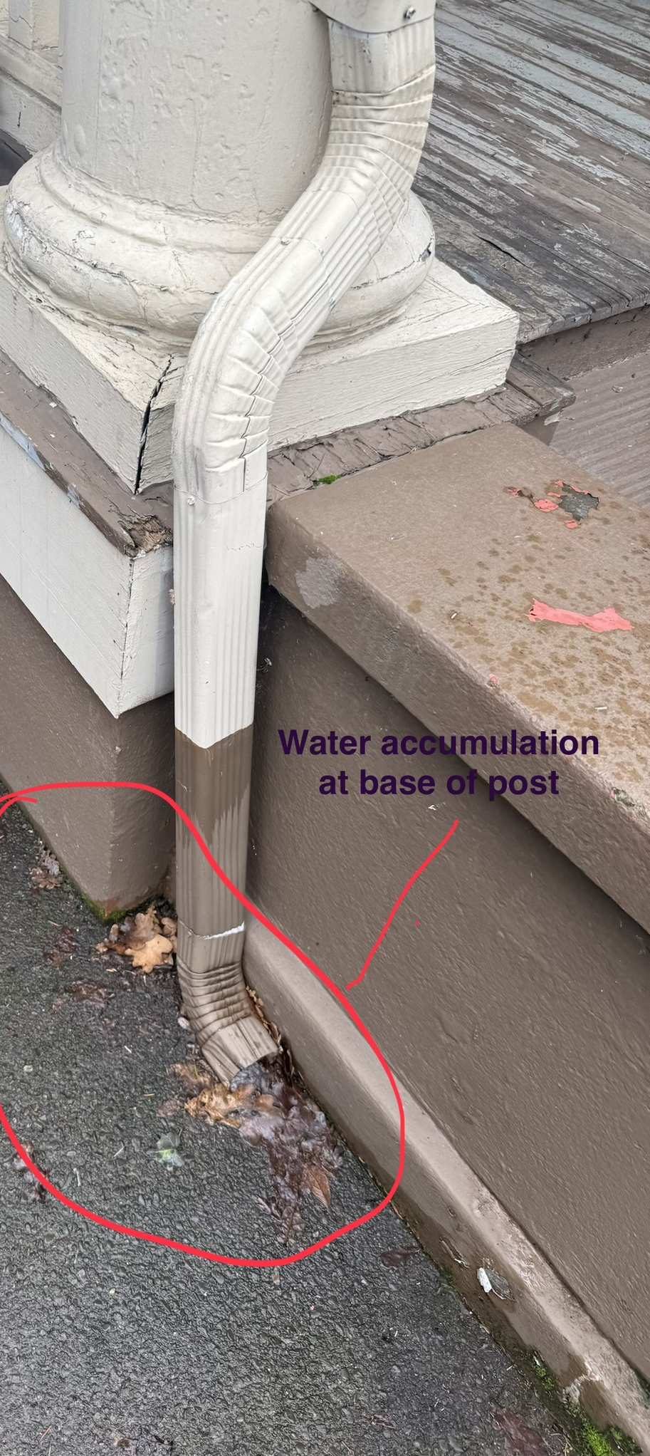 Assessment photo of a downspout draining water at the base of a porch post
