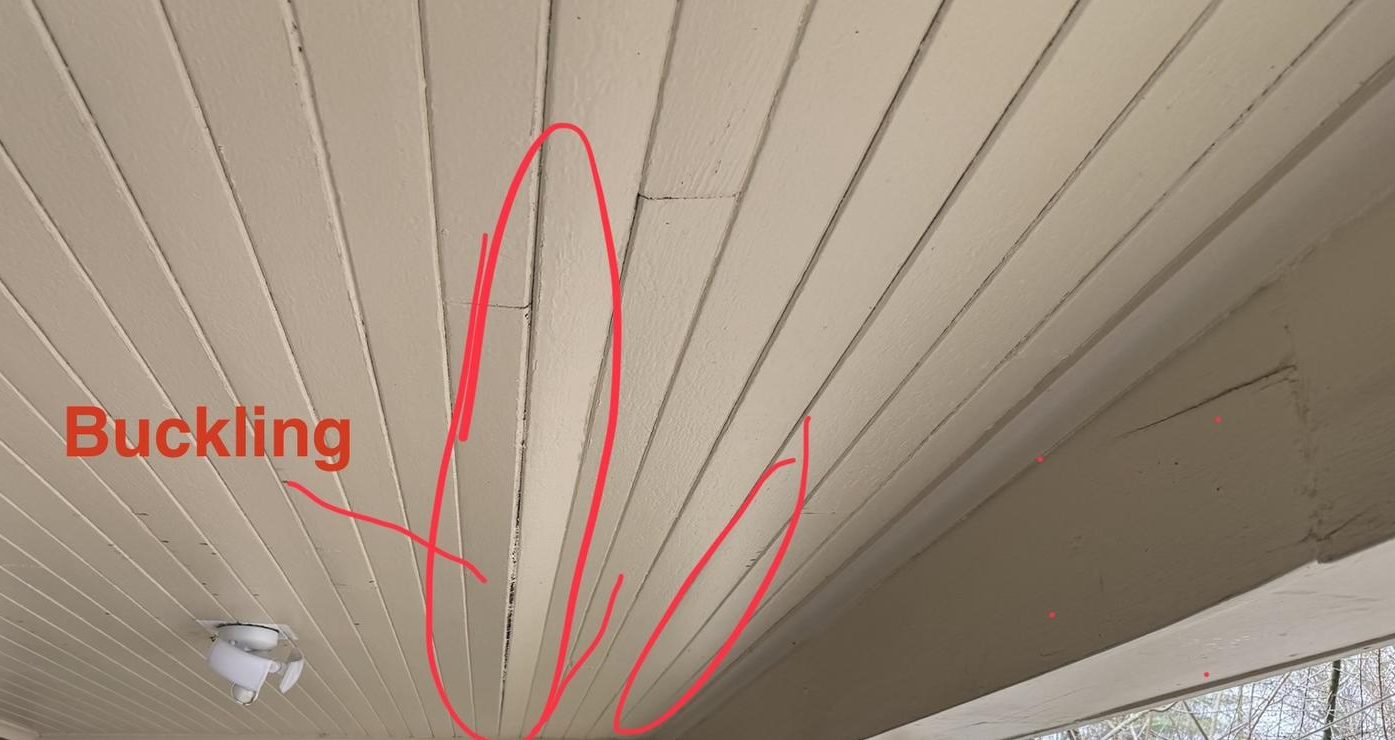 Structural assessment photo of a porch ceiling with buckled soffit boards circled