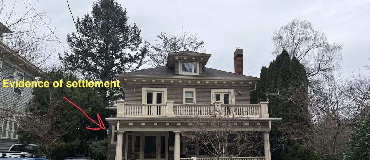 Structural assessment of an older two-story home with an arrow marking evidence of porch settlement