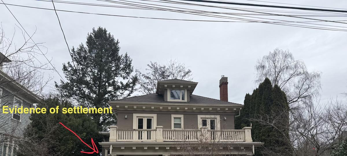 Structural assessment of an older two-story home with an arrow marking evidence of porch settlement